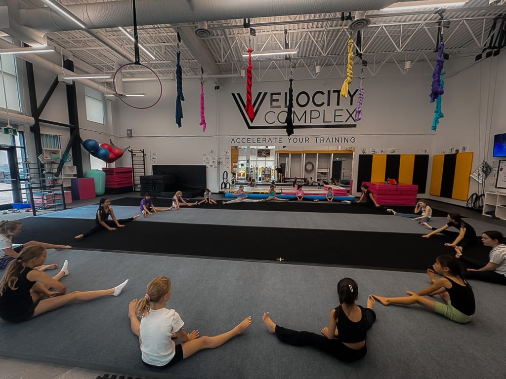 Students sitting in circle stretching at velocity complex summer camp