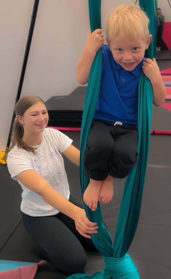 Coach assisting student on aerial silk hammock